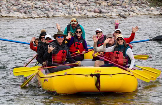 A rafting group smiling and waving at the camera