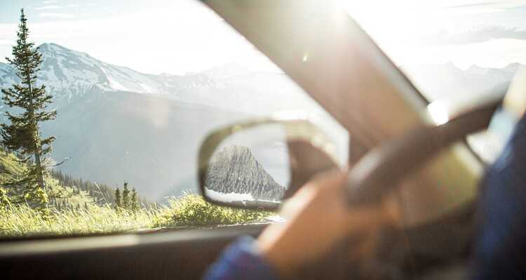 Hands on car steering wheel with a mountain view out the window