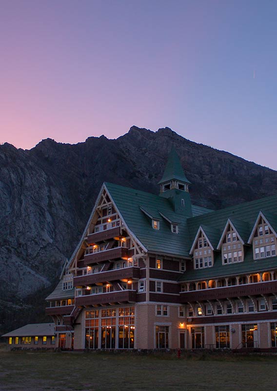 Prince of Wales Hotel exterior lights with a pink sunset sky.